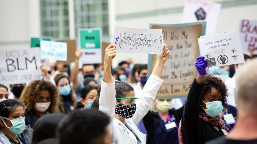 2020 Solidarity Day at UCLA, with a shot of the crowd and a physician holding a sign for #whitecoatsforblacklives