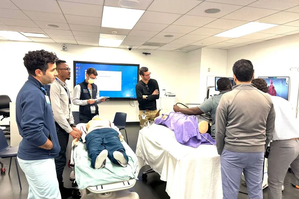 Dr. Yiwombe (second from left) and Mr. Gama (with ultrasound probe, far from right) participated in a special simulation session led by DoM Global Health faculty Daniel Kahn, MD (second from right), Faysal Saab, MD (far left), and Dr. Brook. One case was written by third-year internal medicine resident Richard Brach, MD (center), and Dr. Hodson (third from left) also assisted with the cases. Cardiology faculty Samuel Daneshvar, MD (right) joined as well.