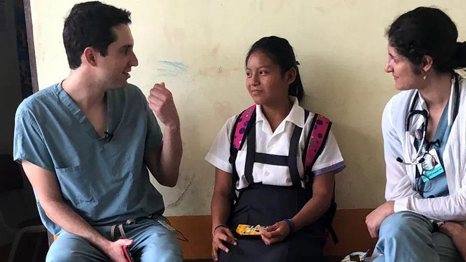DGSOM medical students sitting on a bench with a pediatric patient