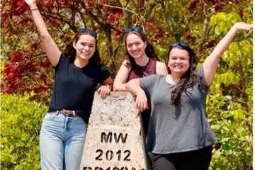 Three MS4 students standing on a rock in Malawi